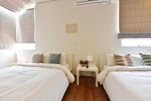 2 camas en una habitación con paredes y ventanas blancas en Penghu Chenhi Bay Homestay, en Baisha