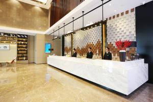 a lobby with three people sitting at a reception counter at Atour Hotel Hangzhou Jinsha Lake in Hangzhou