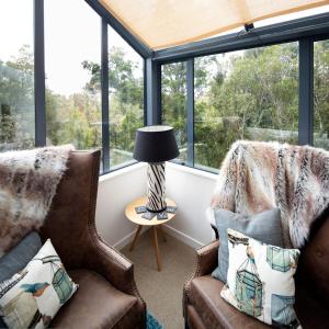 a room with two chairs and a table with a lamp at Love Punakaiki Luxury Couples Retreat Limited in Punakaiki