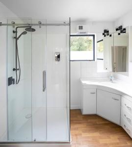 a white bathroom with a shower and a sink at Love Punakaiki Luxury Couples Retreat Limited in Punakaiki +62 photos