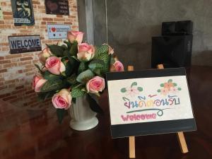 a vase of pink roses with a welcome sign at You In House URT Surathani Airport in Suratthani