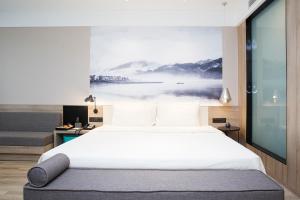 a bedroom with a large bed with a painting on the wall at Atour Hotel Hangzhou Jinsha Lake in Hangzhou