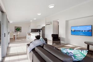 a living room with a couch and a kitchen at Oasis Apartments on Hamilton Island by HIHA in Hamilton Island