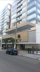 een auto geparkeerd voor een groot gebouw bij quarto social privado ap compartilhado in Capão da Canoa