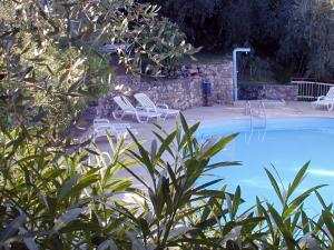 a swimming pool with two chairs and a tree at Residence Castelli in Brenzone sul Garda