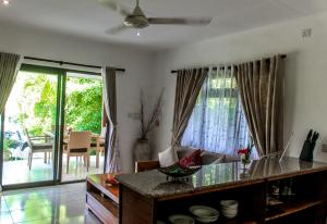 a kitchen with a table and a dining room with sliding glass doors at Surf Tropical Villa Takamaka in Cerf Island