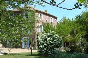 an old brick house with white flowers in front of it at Bastide Rose in Le Thor