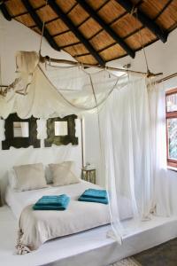 1 dormitorio con 1 cama blanca con dosel en The Little Round House, en Umtwalumi