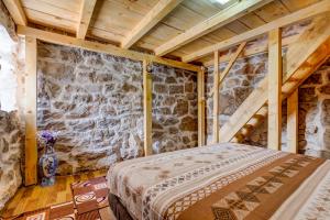 ein Schlafzimmer mit einem Bett in einem Zimmer mit einer Steinmauer in der Unterkunft Ethno House Kosic in Herceg-Novi
