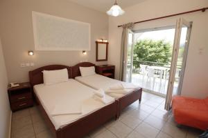 una camera con un grande letto e un balcone di Hotel Afroditi a Paralia Pantaleimonos