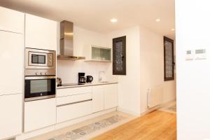 una cocina con armarios blancos y electrodomésticos de acero inoxidable en Akira Flats Urgell apartment, en Barcelona