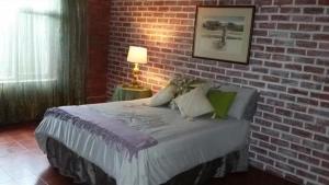 a bedroom with a brick wall and a bed at Isigidi Beach House in Port Shepstone