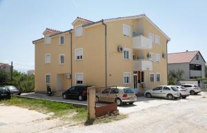 a large yellow building with cars parked in a parking lot at Margareta's Apartment in Kaštela