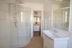 La salle de bains blanche est pourvue d'un lavabo et d'une douche. dans l'établissement Hotel Vila Katrca, à Ljubljana