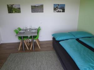 a bedroom with a bed and a table with green chairs at Weinstraßenapartment Fam. Dietrich in Ratsch an der Weinstraße