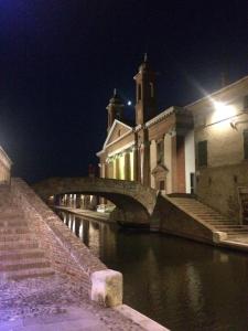 a building with a bridge over a river at night at Locanda della Pescheria in Comacchio