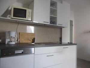 a kitchen with white cabinets and a microwave at Fewo Am Rathausplatz in Freiburg im Breisgau