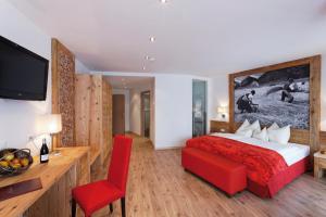 una camera con un grande letto e una sedia rossa di Hotel Amaten a Brunico