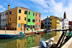 un groupe de bâtiments à côté d'un canal avec des bateaux dans l'établissement LA BRIGATA APARTMENTS Yellow House, à Cavallino-Treporti