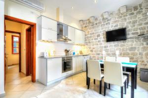 a kitchen with white cabinets and a table and chairs at La Dolce Vita Apartment in Kotor