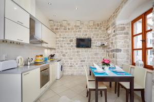 uma cozinha com uma mesa com cadeiras e um lavatório em La Dolce Vita Apartments em Kotor