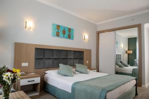 Habitación de hotel con cama y espejo en Adonis Hotel en Antalya
