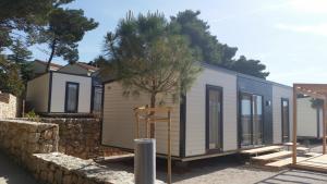 mały domek jest budowany obok kamiennej ściany w obiekcie Adria Village Superior Mobile Homes w Pakoštane