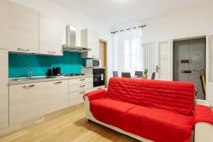 un salon avec un canapé rouge dans une cuisine dans l'établissement Buenos Aires & Lima Cosy Flat, à Milan