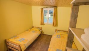 two beds in a small room with a window at Schutzenbach Backpackers For Adults 18-32 years only in Lauterbrunnen +41 photos