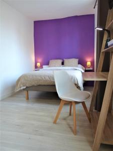 ein Schlafzimmer mit einem Bett mit einer lila Wand in der Unterkunft Les Clochers d'Or in Chartres