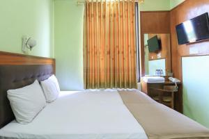 sypialnia z białym łóżkiem i telewizorem na ścianie w obiekcie Hotel Prisma w mieście Sidoarjo