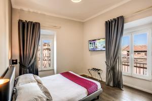 a bedroom with a bed and two windows and a tv at Piccola Navona Roof Garden in Rome