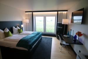 a hotel room with a bed and a desk and a window at GI Hotel by WMM Hotels in Giengen an der Brenz