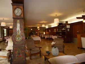 une grande horloge grand-père dans un salon avec des chaises dans l'établissement Hôtel Le Castelet, à Ax-les-Thermes