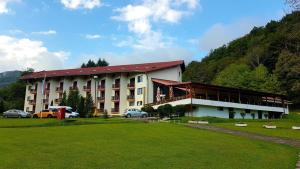 a large building with cars parked in front of it at Hotel Mladost in Tjentište