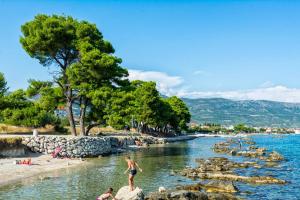a group of people standing on rocks in the water at Apartment Bella Costa I in Kaštela +21 photos