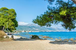 a beach with trees and people on the water at Apartment Bella Costa I in Kaštela