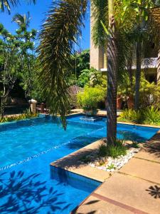 una piscina con una palmera al lado de un edificio en Cumbuco Apartment Rentals, en Cumbuco