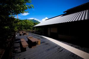 una terraza de madera con bancos junto a un edificio en Yufuin Gettouan en Yufuin