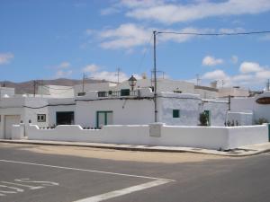 a white building with a fence on the side of a street at Casa Callao in Famara