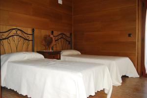 2 camas en una habitación con paredes de madera en casa rural La Gabina, en Muñogalindo