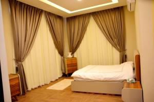 a bedroom with a bed and drapes at Chalet Al Mas Kortoba in Riyadh