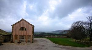 a barn on a gravel road next to a field at The Hayloft in Skipton