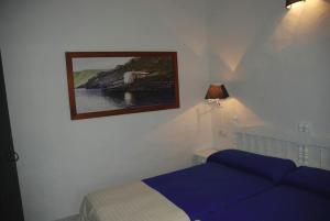 Un dormitorio con una cama azul y una foto en la pared en Agroturisme Binisaid NOU, en Cala Galdana