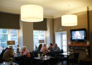 a group of people sitting at tables in a restaurant at De Pastorie Bed & Breakfast in Roermond