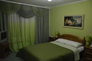 a bedroom with a bed with green walls and curtains at Knaus Apartments in Chernivtsi