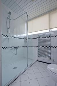 a white bathroom with a shower and a sink at At Sea in Katwijk aan Zee