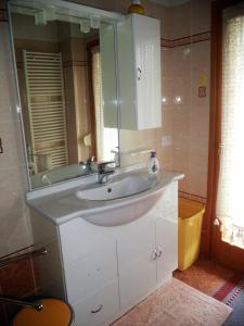 uma casa de banho com um lavatório branco e um espelho. em B&B Dolomiti em Calalzo