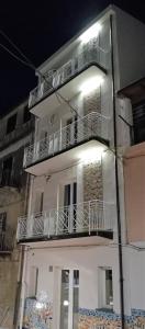 un edificio blanco con balcones y luces. en Case Vacanza Le Casette en Santo Stefano di Camastra