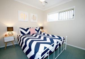 a bedroom with a black and white striped bed and a window at Anaheim Entertainer by Getastay in Gold Coast